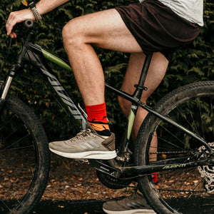 Person wearing Kangaroo Sunset Crew Socks in red, orange, yellow and black cotton